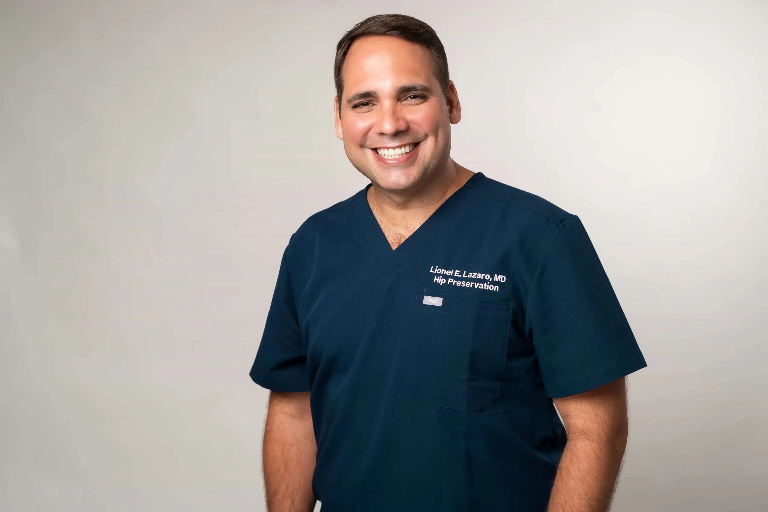 El Dr. Lionel Lázaro, cirujano ortopeda, sonriendo en su uniforme quirúrgico